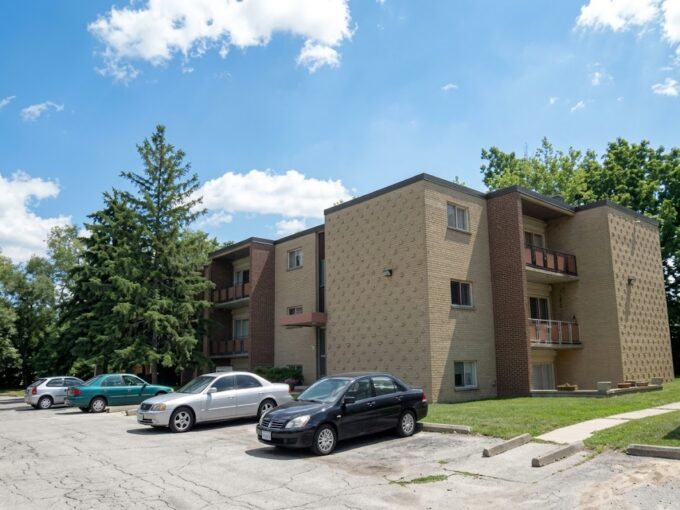 Three-story brick apartment building at 200 Commissioners Rd W with parking lot and trees