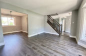 large room with wooden floor leading to another room to the left and staircase ahead