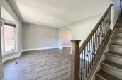 view of large room with wooden floor from bottom of staircase