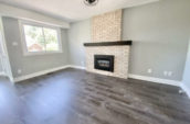 empty room with wooden floor and brick fireplace